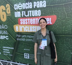 Maely Oliveira, usando trajes na cor verde no banner da 6º Ciência para um futuro sustentável e inclusivo.