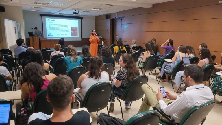 A imagem exibe um auditório com pessoas assistindo uma palestra do evento "Wikimedia e Ciência: potencialidades na extensão e difusão científica".